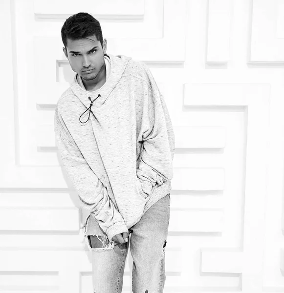 Genç yakışıklı modeli adam portresi dokulu beyaz duvara yakın poz gri rahat Kapşonlu elbise giymiş