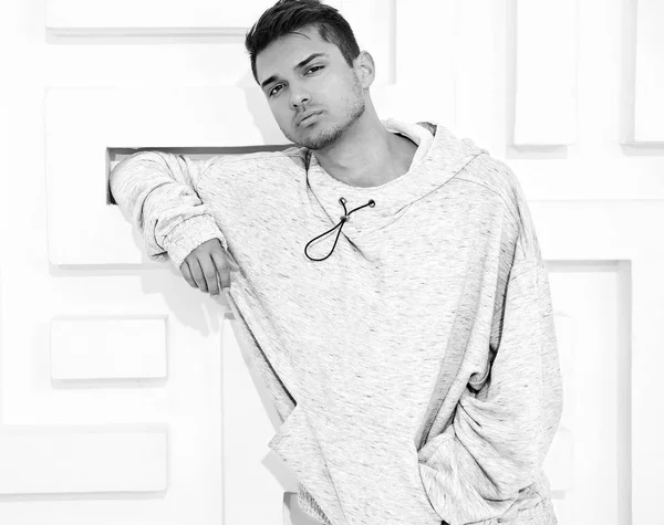 Genç yakışıklı modeli adam portresi dokulu beyaz duvara yakın poz gri rahat Kapşonlu elbise giymiş