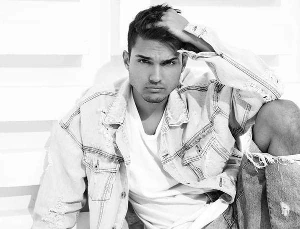 Yakışıklı genç model adam portresi beyaz dokulu duvara yakın oturan kot elbise giymiş