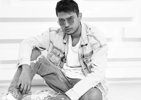 Yakışıklı genç model adam portresi beyaz dokulu duvara yakın oturan kot elbise giymiş