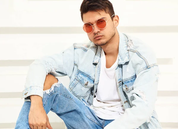 Yakışıklı genç model adam portresi beyaz dokulu duvara yakın oturan kot elbise giymiş