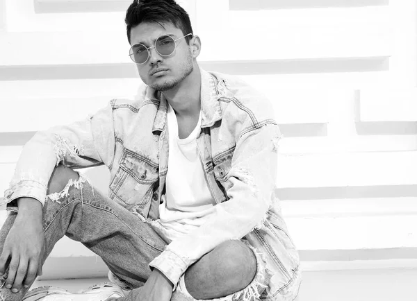 Yakışıklı genç model adam portresi beyaz dokulu duvara yakın oturan kot elbise giymiş