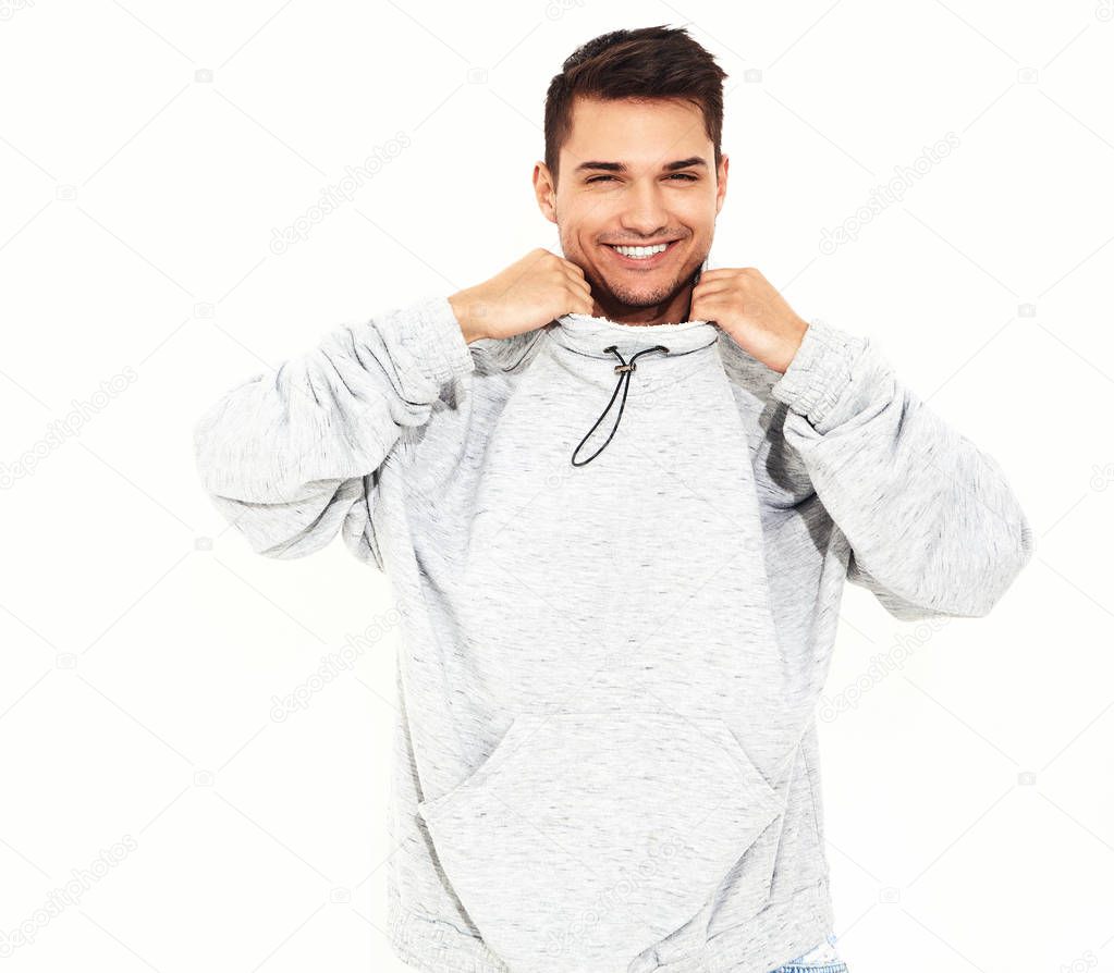 Portrait of young smiling handsome model man dressed in gray casual hoodie clothes posing on white background. Isolated