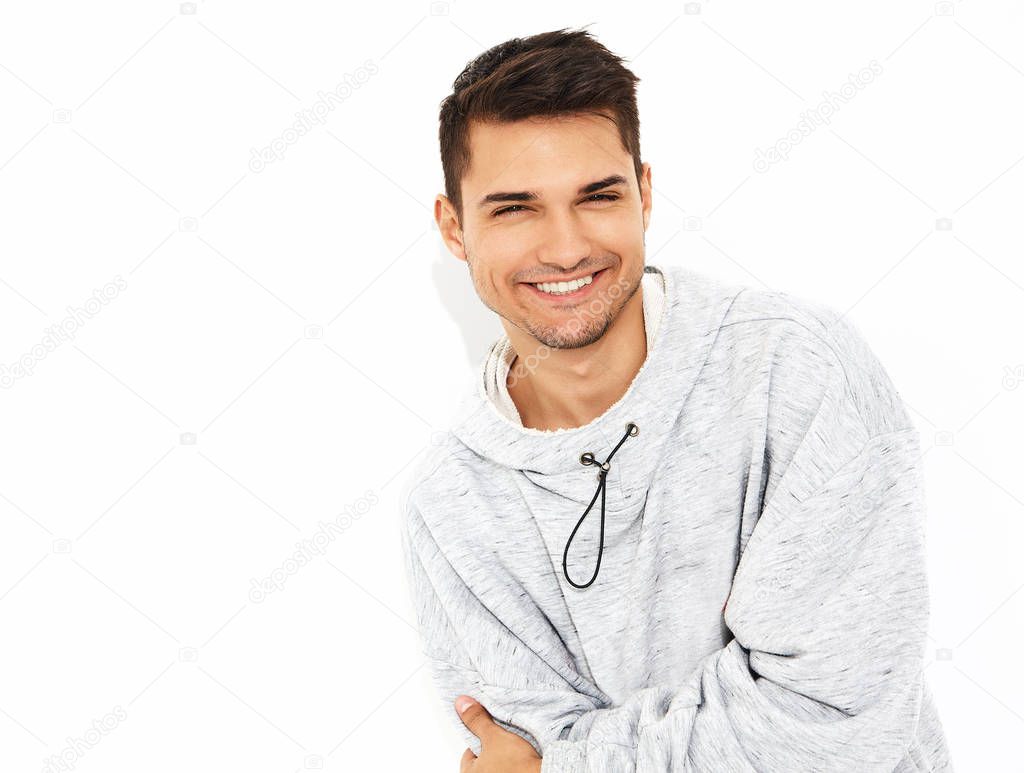 Portrait of young smiling handsome model man dressed in gray casual hoodie clothes posing on white background. Isolated
