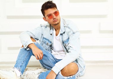 Yakışıklı genç model adam portresi beyaz dokulu duvara yakın oturan kot elbise giymiş