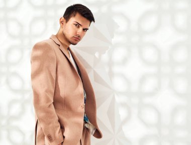 Moda şık lumbersexual modeli Studio beyaz duvarının yakınında poz zarif ışık pembe takım elbise giymiş. Metroseksüel