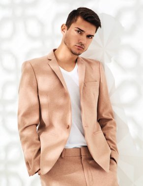 Moda şık lumbersexual modeli Studio beyaz duvarının yakınında poz zarif ışık pembe takım elbise giymiş. Metroseksüel