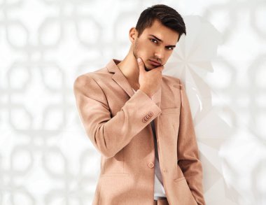 Moda şık lumbersexual modeli Studio beyaz duvarının yakınında poz zarif ışık pembe takım elbise giymiş. Metroseksüel