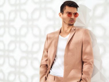 Moda şık lumbersexual modeli Studio beyaz duvarının yakınında poz zarif ışık pembe takım elbise giymiş. Metroseksüel