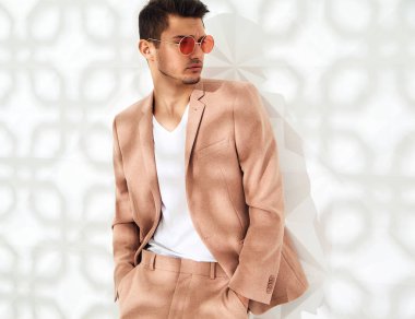 Moda şık lumbersexual modeli Studio beyaz duvarının yakınında poz zarif ışık pembe takım elbise giymiş. Metroseksüel