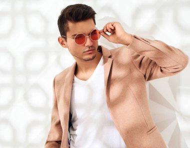 Moda şık lumbersexual modeli Studio beyaz duvarının yakınında poz zarif ışık pembe takım elbise giymiş. Metroseksüel