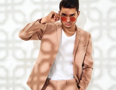 Moda şık lumbersexual modeli Studio beyaz duvarının yakınında poz zarif ışık pembe takım elbise giymiş. Metroseksüel