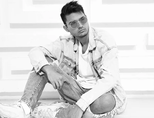 Yakışıklı genç model adam portresi beyaz dokulu duvara yakın oturan kot elbise giymiş