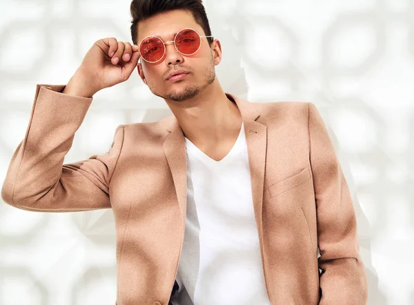 Moda şık lumbersexual modeli Studio beyaz duvarının yakınında poz zarif ışık pembe takım elbise giymiş. Metroseksüel