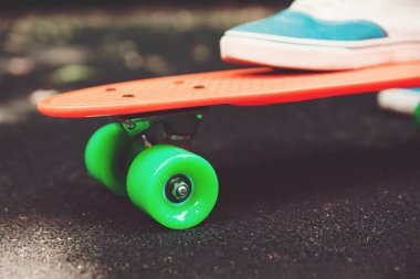 Ayak kız spor ayakkabı rides asfalt üzerinde turuncu kuruş kaykay üzerinde Kapat
