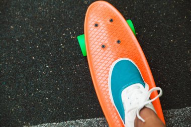 Ayak kız spor ayakkabı rides asfalt üzerinde turuncu kuruş kaykay üzerinde Kapat