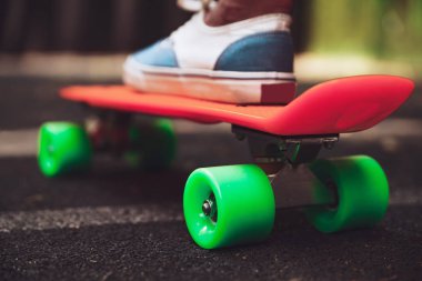 Ayak kız spor ayakkabı rides asfalt üzerinde turuncu kuruş kaykay üzerinde Kapat