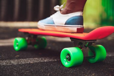Ayak kız spor ayakkabı rides asfalt üzerinde turuncu kuruş kaykay üzerinde Kapat