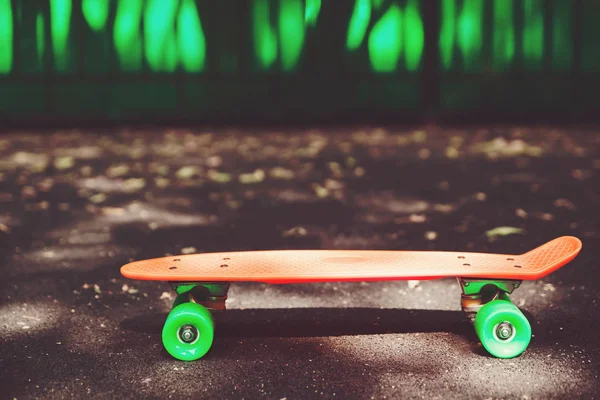 Εσωτερικη Πορτοκαλί Δεκάρα Skateboard Στην Άσφαλτο Πίσω Από Πράσινο Τοίχο — Φωτογραφία Αρχείου