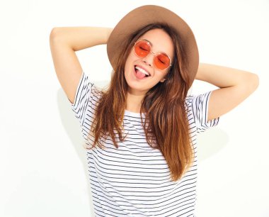 Genç şık gülen kız modeli rahat yaz giysileri ile doğal makyaj beyaz arka plan üzerinde izole kahverengi şapkalı portresi. Dilini gösterilen