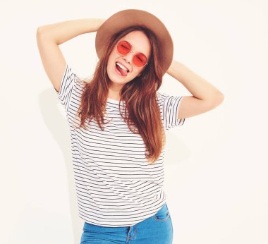 Genç şık gülen kız modeli rahat yaz giysileri ile doğal makyaj beyaz arka plan üzerinde izole kahverengi şapkalı portresi. Dilini gösterilen