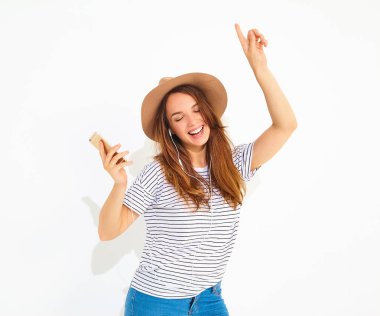 güzel gülen esmer kadın kız rahat hipster yaz giysileri kahverengi şapka dinleme müzik kulaklık ile smartphone içinde hiç makyaj ile