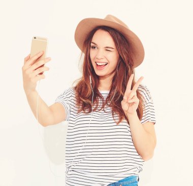 Yaz hipster giysileri beyaz arka plan üzerinde izole bir selfie alarak güzel bir kız portresi. Göz kırpıyor ve barış işareti gösterilen