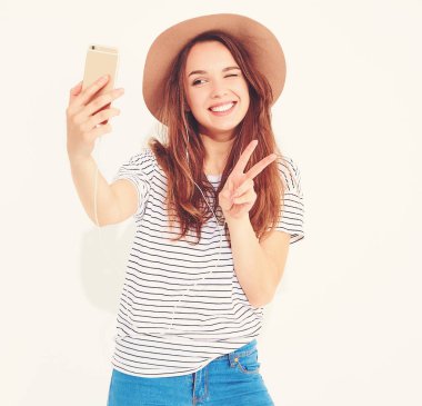 Yaz hipster giysileri beyaz arka plan üzerinde izole bir selfie alarak güzel bir kız portresi. Göz kırpıyor ve barış işareti gösterilen