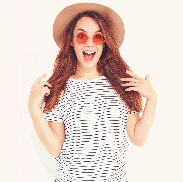 Sürpriz rahat yaz giysileri ile doğal makyaj beyaz arka plan üzerinde izole kahverengi şapkalı yüz ifadesi ile portre genç şık kız modeli. Kameraya bakarak