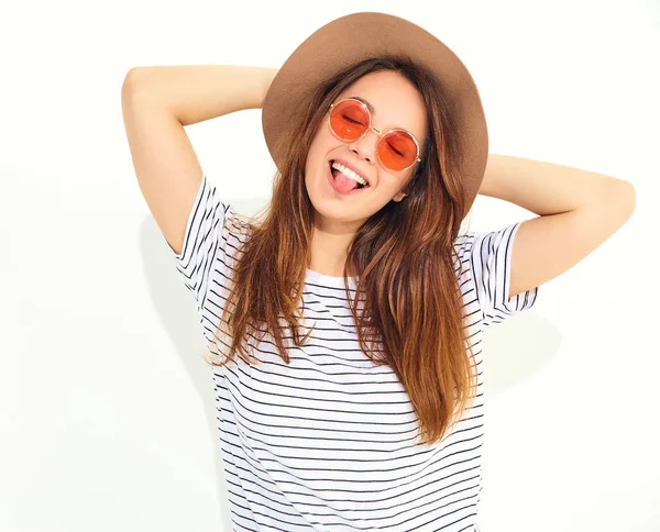 Genç şık gülen kız modeli rahat yaz giysileri ile doğal makyaj beyaz arka plan üzerinde izole kahverengi şapkalı portresi. Dilini gösterilen