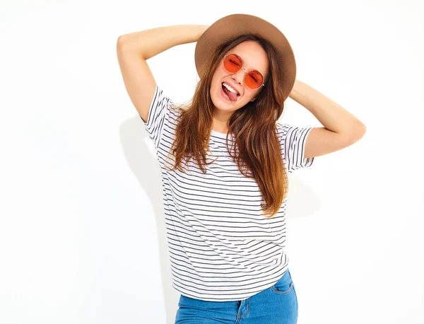 若いスタイリッシュな笑う少女モデル ナチュラルメイクは 白い背景で隔離の茶色の帽子でカジュアルな夏服 まばたきと彼女の舌を表示 — ストック写真