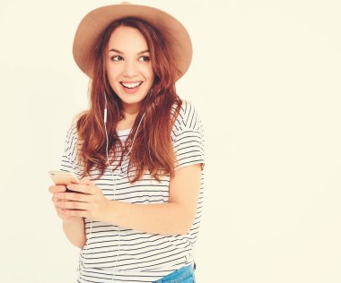 güzel gülen esmer kadın kız rahat hipster yaz giysileri kahverengi şapka dinleme müzik kulaklık ile smartphone içinde hiç makyaj ile