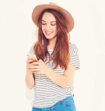 güzel gülen esmer kadın kız rahat hipster yaz giysileri kahverengi şapka dinleme müzik kulaklık ile smartphone içinde hiç makyaj ile