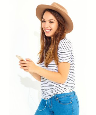 hiç makyaj smartphone üzerinde beyaz izole kulaklık ile kahverengi şapka dinleme müzik ile güzel kız rahat hipster yaz giysileri. Dans