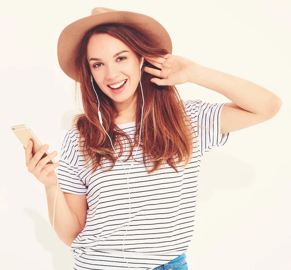 güzel gülen esmer kadın kız rahat hipster yaz giysileri kahverengi şapka dinleme müzik kulaklık ile smartphone içinde hiç makyaj ile