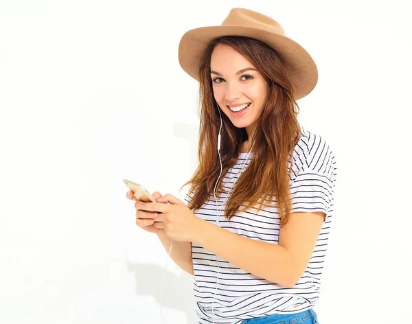 hiç makyaj smartphone üzerinde beyaz izole kulaklık ile kahverengi şapka dinleme müzik ile güzel kız rahat hipster yaz giysileri. Dans