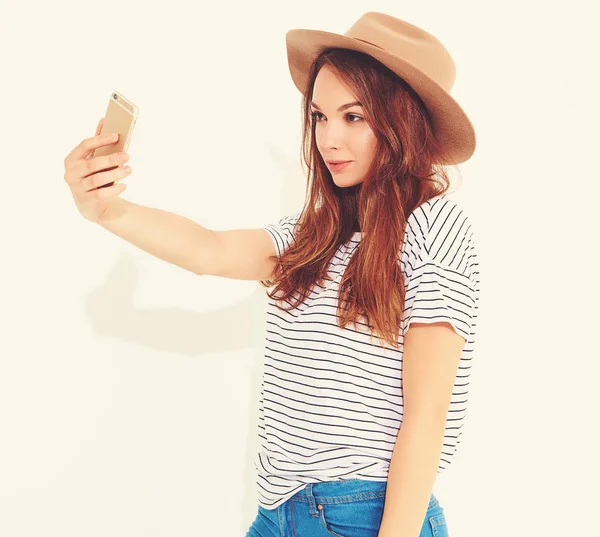 Portrait of a pretty girl in summer hipster clothes taking a selfie isolated on white background