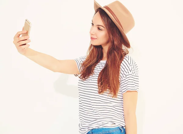 Portrait of a pretty girl in summer hipster clothes taking a selfie isolated on white background