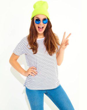 Portre rahat yaz aylarında genç şık kız modelinin üzerinde beyaz izole sarı bere şapka elbise. Barış işareti gösterilen