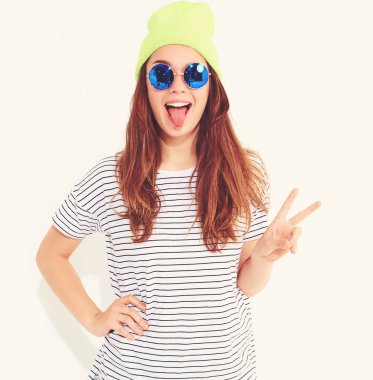 Portre rahat yaz aylarında genç şık kız modelinin üzerinde beyaz izole sarı bere şapka elbise. Barış işareti gösterilen