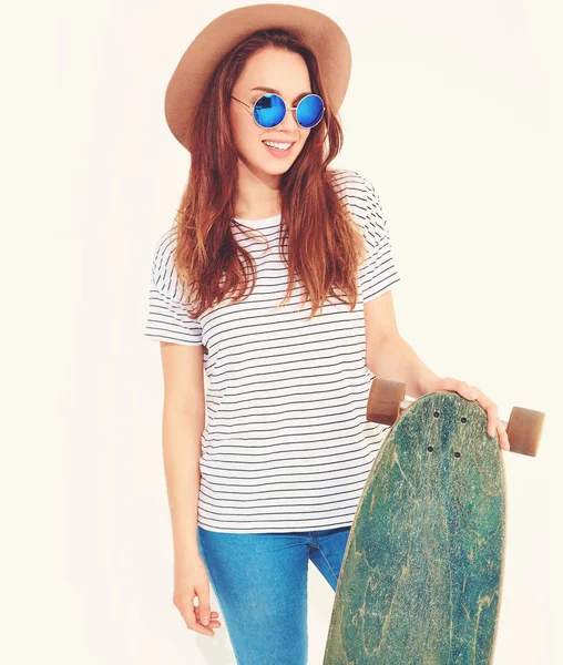 ロングボード デスクでポーズ茶色の帽子でカジュアルな夏服でスタイリッシュな少女モデルの肖像画 白で隔離 — ストック写真