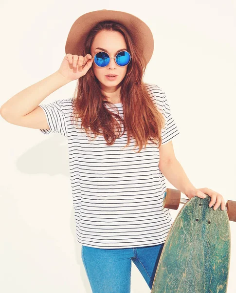 Portre rahat yaz giysileri longboard resepsiyon ile poz kahverengi şapkalı şık kız modeli. Beyaz izole