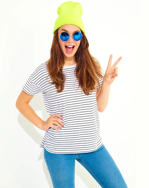 Portre rahat yaz aylarında genç şık kız modelinin üzerinde beyaz izole sarı bere şapka elbise. Barış işareti gösterilen