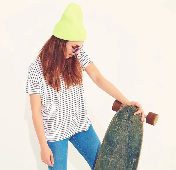 Portre rahat yaz giysileri longboard resepsiyon ile poz sarı beanie şapkalı şık kız modeli. Beyaz izole