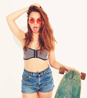 genç şık gülümseyen kız modeli rahat yaz mayo giysileri longboard resepsiyon ile poz. Dilini gösterilen