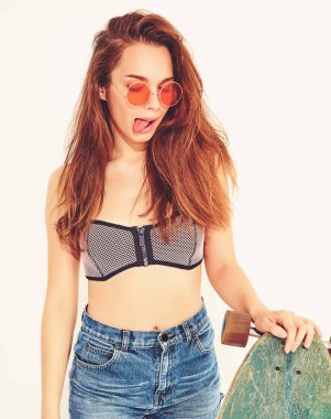 genç şık gülümseyen kız modeli rahat yaz mayo giysileri longboard resepsiyon ile poz. Dilini gösterilen