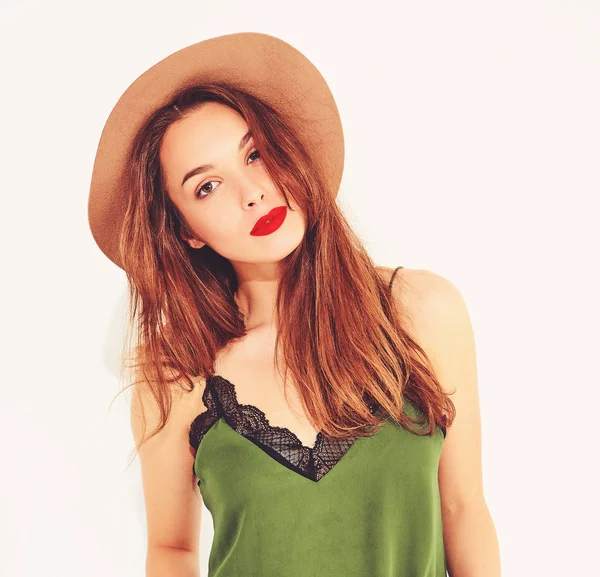 Genç şık kız modeli rahat yaz yeşil giysiler ve kırmızı dudaklı beyaz duvara yakın poz, kahverengi şapka