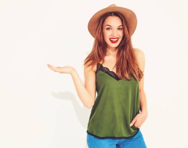 Genç şık kız modeli rahat yaz yeşil giysiler ve kırmızı dudaklar bir şey elinde izole, holding ile kahverengi şapka 