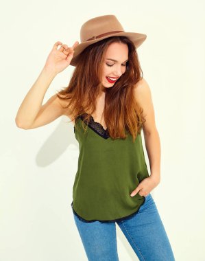 Genç şık kız modeli rahat yaz yeşil giysiler ve kırmızı dudaklı beyaz duvara yakın poz, kahverengi şapka