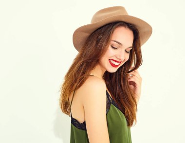 Genç şık kız modeli rahat yaz yeşil giysiler ve kırmızı dudaklı beyaz duvara yakın poz, kahverengi şapka